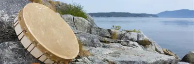 indigenous drum with baton on rock overlooking the water